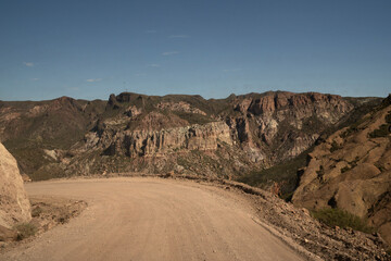 Fototapeta na wymiar Travel. View of the dirt road across the arid desert and mountains.