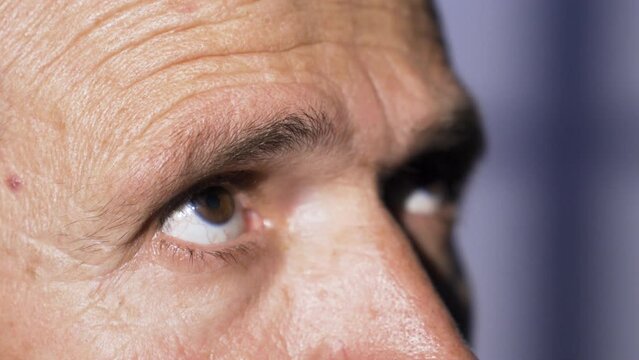 Close-up of anxious male eyes.
The man, who is uneasy in his environment, looks around from the corner of his eye.

