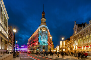 Cruce de las Calles Sevilla y Alcalá con el Edificio Canalejas adornado con elementos navideños en el centro, albergando las Galerías Canalejas y un Hotel Four Seasons.