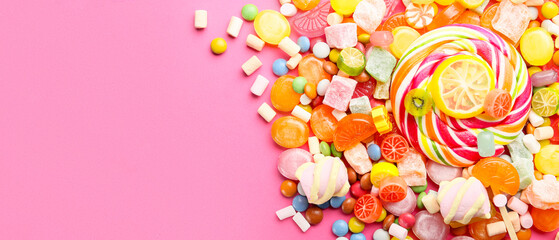 Assortment of sweet candies on pink background with space for text