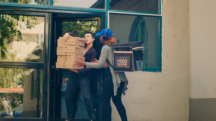 Female delivery worker carrying pile of pizza boxes to deliver restaurant order to customer, food...