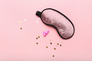 Earplugs and sleeping mask on pink background