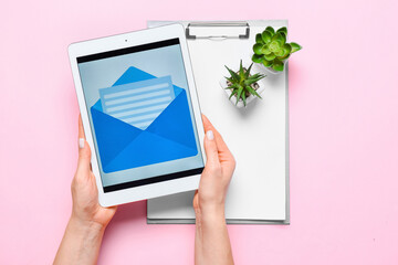 Woman holding tablet computer new unread message, clipboard and houseplants on pink background