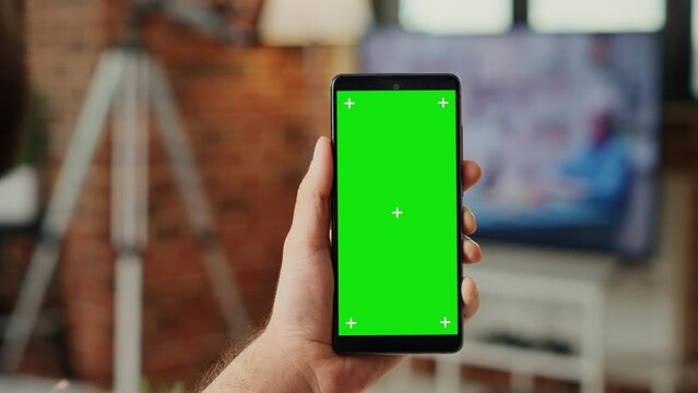 Office worker working with greenscreen template on mobile phone, using smartphone with blank background and chroma key display. Looking at isolated mock up copy space. Close up.