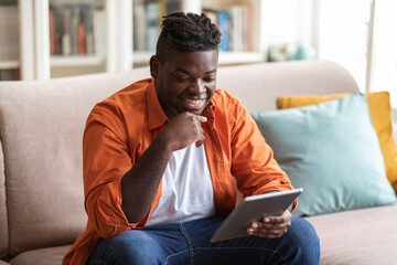 Happy young black man watching video on digital tablet