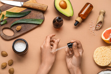 Woman applying essential oil onto her hand on color background