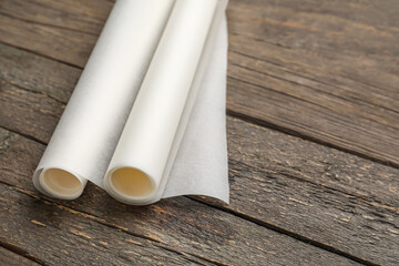 Rolls of baking paper on wooden background, closeup