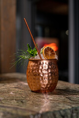 Close up on a copper cup with Moscow Mule cocktail, fresh mint as decoration and a white and...