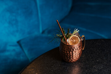 Close up on a copper cup with Moscow Mule cocktail, fresh mint as decoration and a white and...