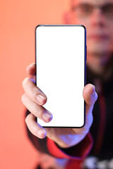 smartphone with a white screen vertically in the hand against the backdrop of a person