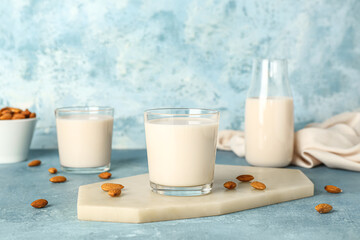 Board with glass of healthy almond milk on color background