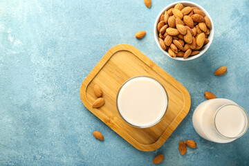 Fototapeta na wymiar Glass, bottle of almond milk and nuts on color background