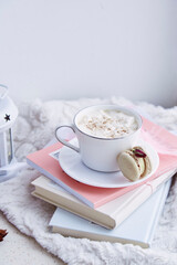 Aesthetics breakfast with hot drink with foam, delicate macaroon on the books. Sweet dessert at cozy home