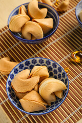 Bowls of fortune cookies and Chinese symbols on bamboo mat, closeup