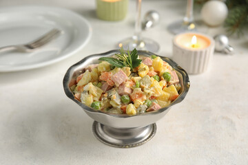 Metal bowl of tasty Olivier salad on light table