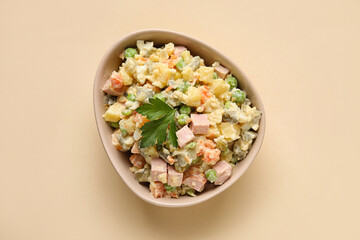 Bowl of delicious Olivier salad on color background