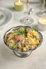 Metal bowl of tasty Olivier salad on light table
