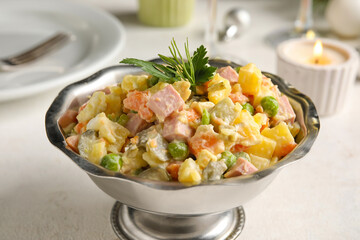 Metal bowl of tasty Olivier salad on light table, closeup