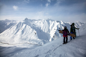 A couple of freeriders climb the big winter mountains in front of a spectacular view