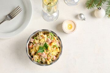 Bowl of tasty Olivier salad, burning candle and glass of champagne on light background