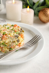 Plate of tasty Olivier salad on light table, closeup