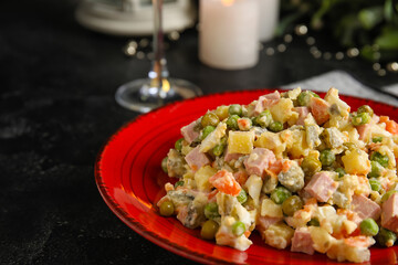 Plate of tasty Olivier salad on dark background, closeup