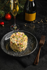 Plate with tasty Olivier salad and glass of champagne on dark background
