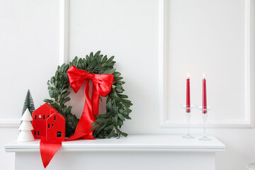 Christmas wreath with candle holders and fir trees on mantelpiece in light living room - obrazy, fototapety, plakaty