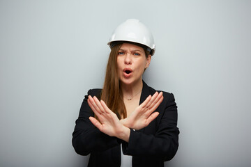 Woman architect or engineer in white helmet doing stop symbol with crossed hands. Isolated female portrait.