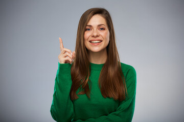Smiling woman in green pointing finger up. Isolated advertising portrait.