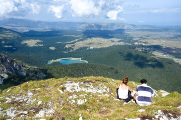 Hikers on the top of the mountain with the lake and forest beneath them.