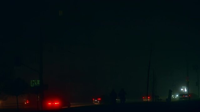 Two dark silhouettes of men walking along the road full of cars. Blackout time in Ukraine after russian drone and missiles attacks. City in darkness from energy outage.