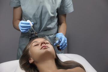 Cosmetologist applying serum on client's face in salon