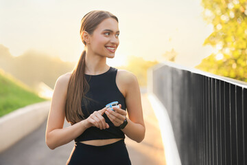 Happy woman checking pulse with blood pressure monitor on finger after training outdoors. Space for text