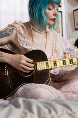 woman with blue hair playing antique guitar at home