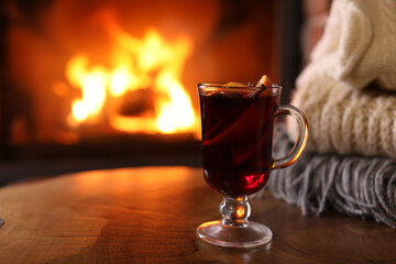 Tasty mulled wine, knitwear and blurred fireplace on background