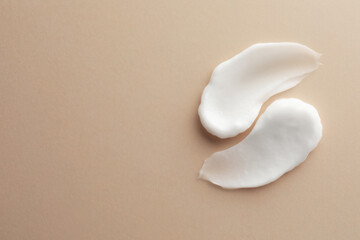 Sample facial cream on beige background, top view. Space for text