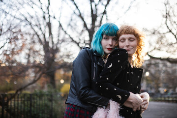 unconventional lesbian couple embrace in park at sunset