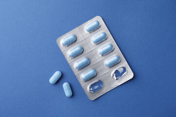 Pills on blue background, top view. Potency problem