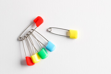 Colorful safety pins on white background, flat lay. Space for text