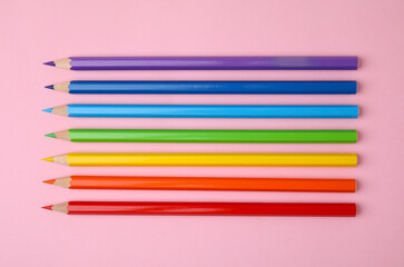 Colorful wooden pencils on pink background, flat lay
