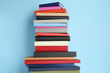 Stack of different books on light blue background