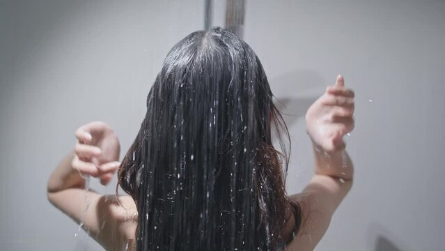 She takes a shower and uses shampoo as an Asian woman.