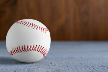 Baseball ball on grey wooden table, closeup. Space for text