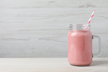 Mason jar with delicious berry smoothie on white wooden table. Space for text