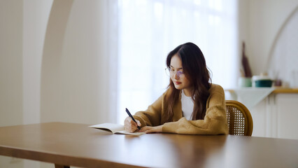 Beautiful young asian woman sitting and taking note at house. Happy smiling working online,...