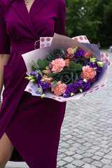 Big luxury bouquet of purple flowers in woman hands