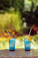 Two glasses of a cocktail drinks placed on a marble table with green background, copy space