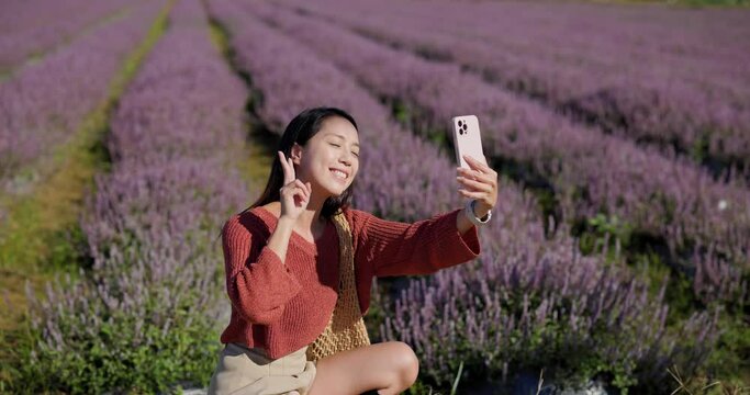 Beautiful Asian woman in Chinese Mesona flower field to take selfie on cellphone in Taoyuan Yangmei District