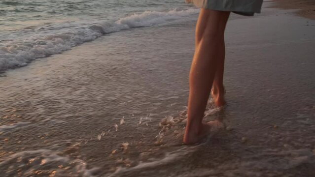 beautiful girl on the beach at sunset running along the shore. a girl enjoys the sunset on the ocean. a girl walks on the waves